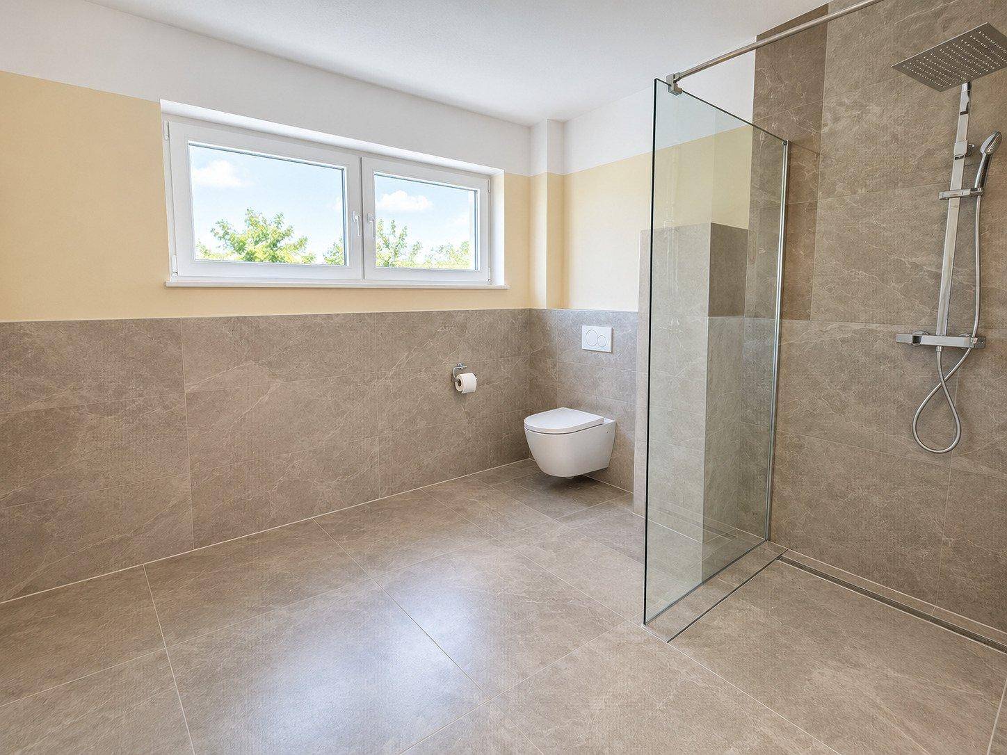 Modernes Badezimmer mit großformatigen Fliesen, ebenerdiger Dusche und Fenster.