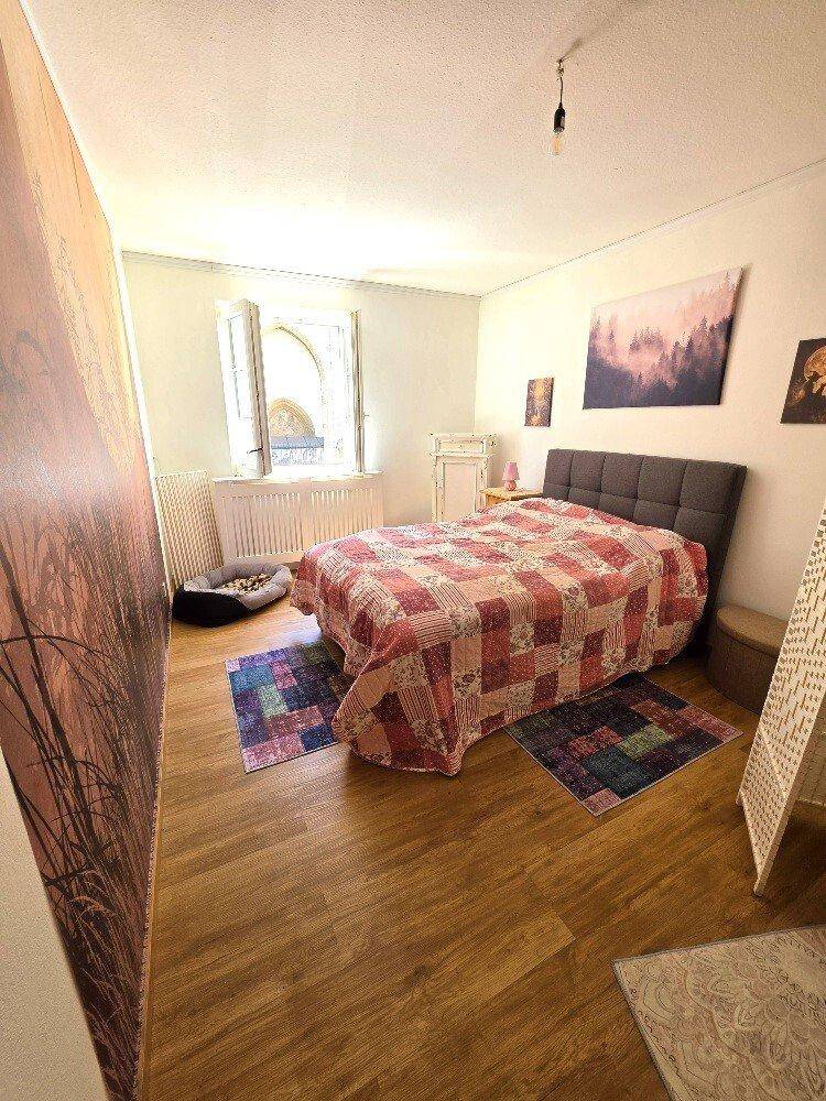 Helles Schlafzimmer mit Holzboden, einem bequemen Bett und einem Fenster mit Blick nach draußen.