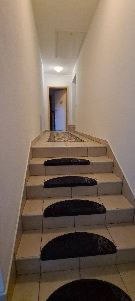 Treppenhaus mit gefliesten Stufen und Teppichläufern, führt in die obere Etage.