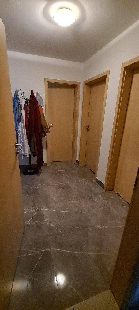 Flur mit dunklen Fliesen, Garderobe und Zugang zu verschiedenen Zimmern.