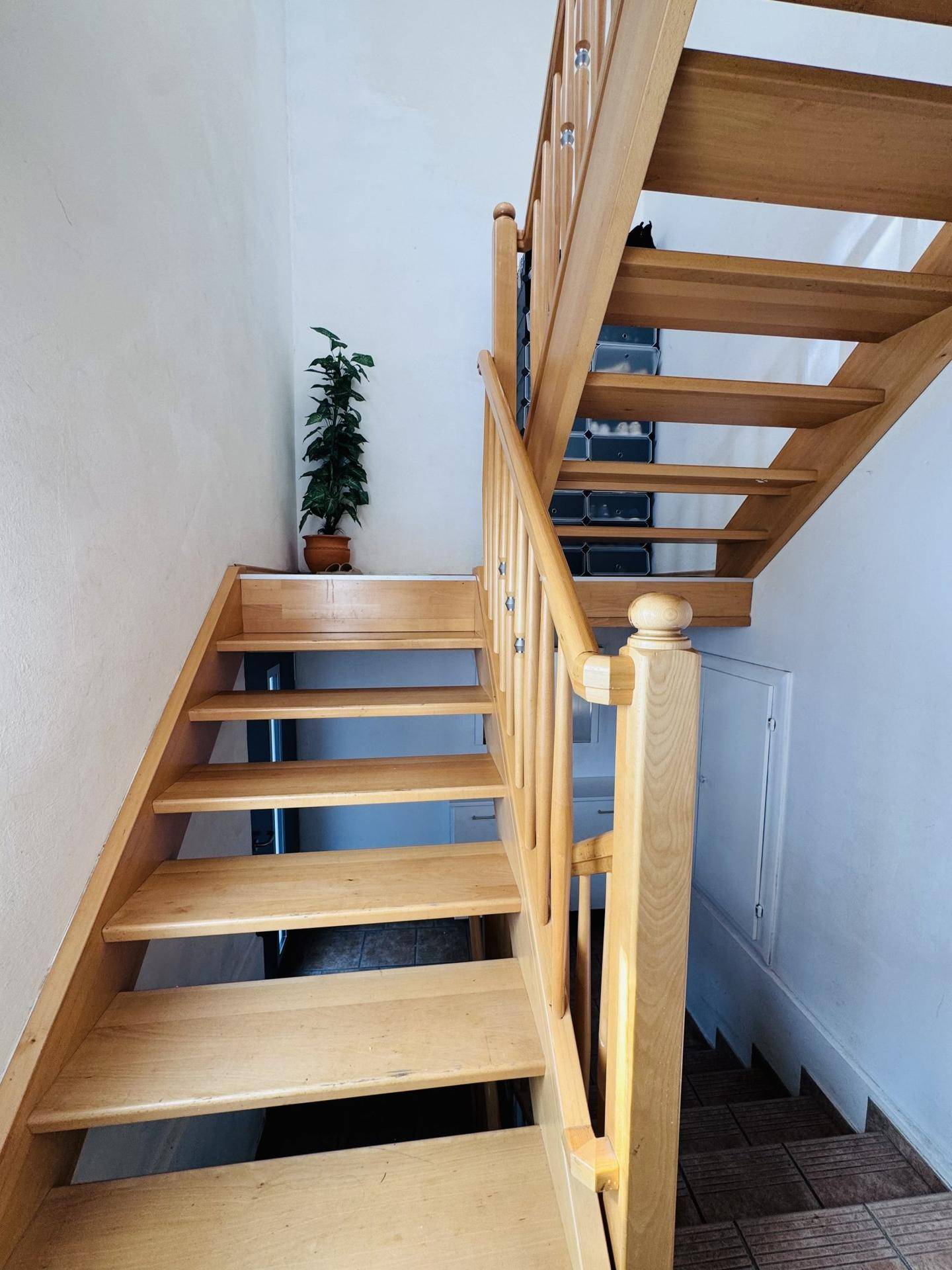 Helle Holztreppe mit Geländer, die in die obere Etage führt.