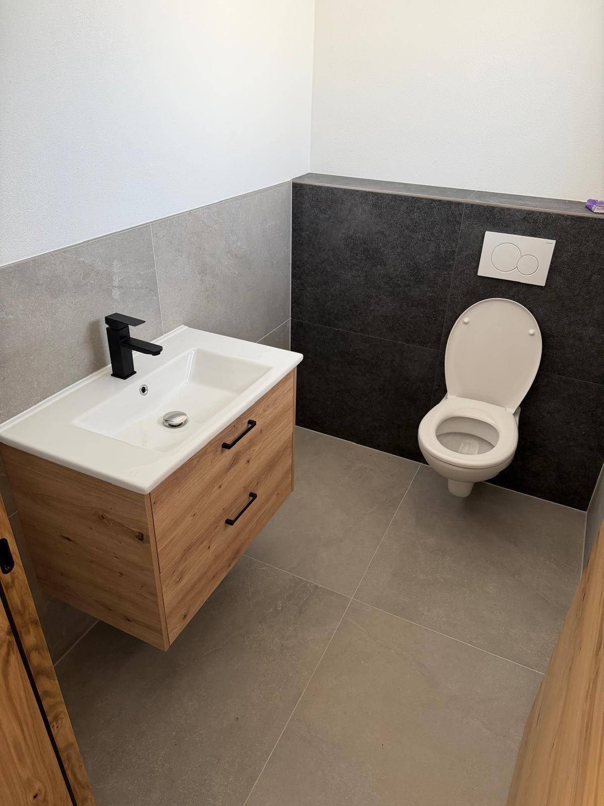 Kleines Gäste-WC mit modernem Waschtisch, wandhängendem WC und zweifarbiger Wandgestaltung.