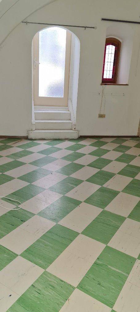 Raum mit auffälligem grün-weiß kariertem Boden und einem ungewöhnlichen Bogenfenster.