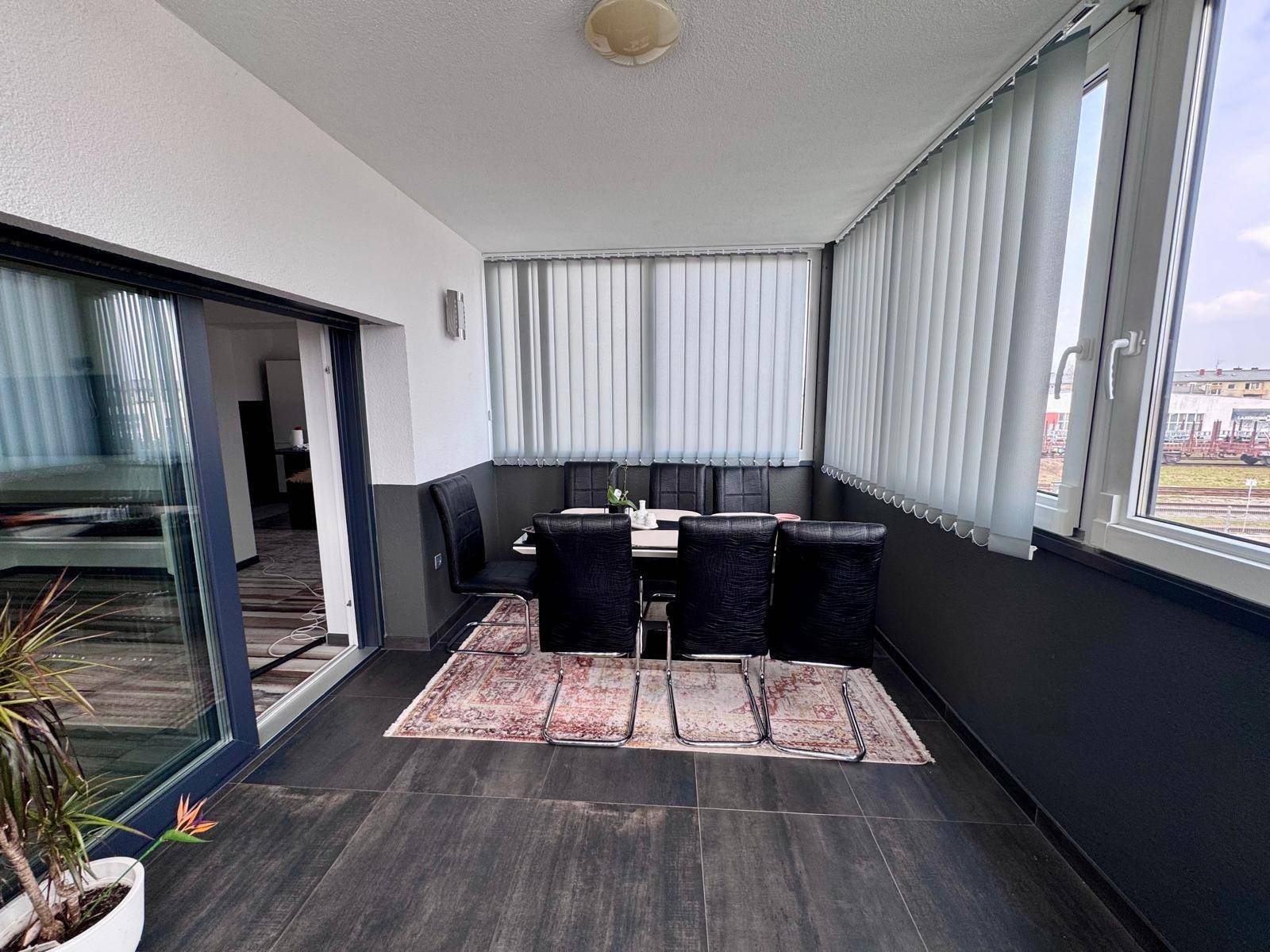 Verglaste Loggia, eingerichtet als Essbereich mit Blick nach draußen.