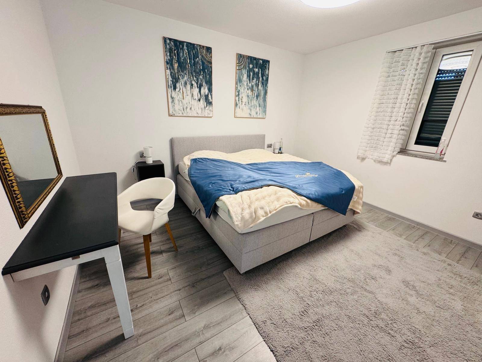 Ruhiges Schlafzimmer mit Doppelbett, Nachttischen und modernem Bodenbelag.