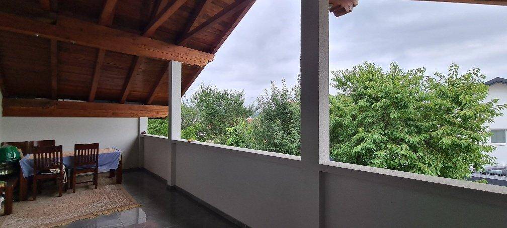 Überdachter Balkon mit Holzdach und Essbereich, umgeben von Bäumen.