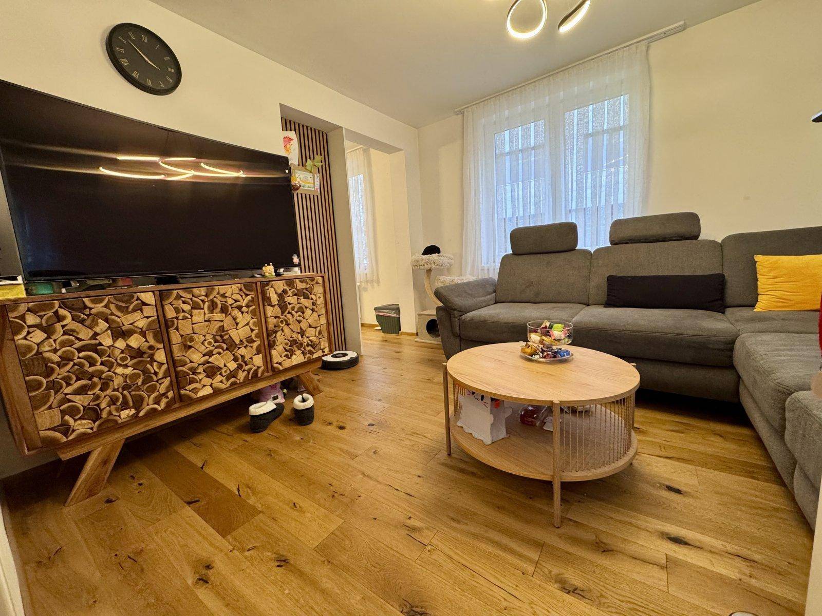 Gemütliches Wohnzimmer mit großem Ecksofa, Holzboden und modernem TV-Möbel.