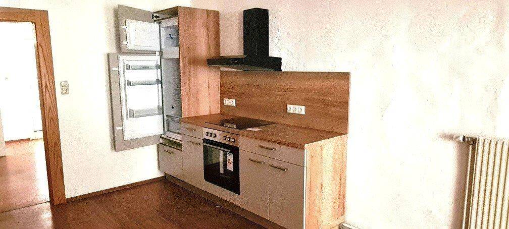 Moderne Einbauküche mit Holzfronten, integriertem Kühlschrank und Kochfeld.