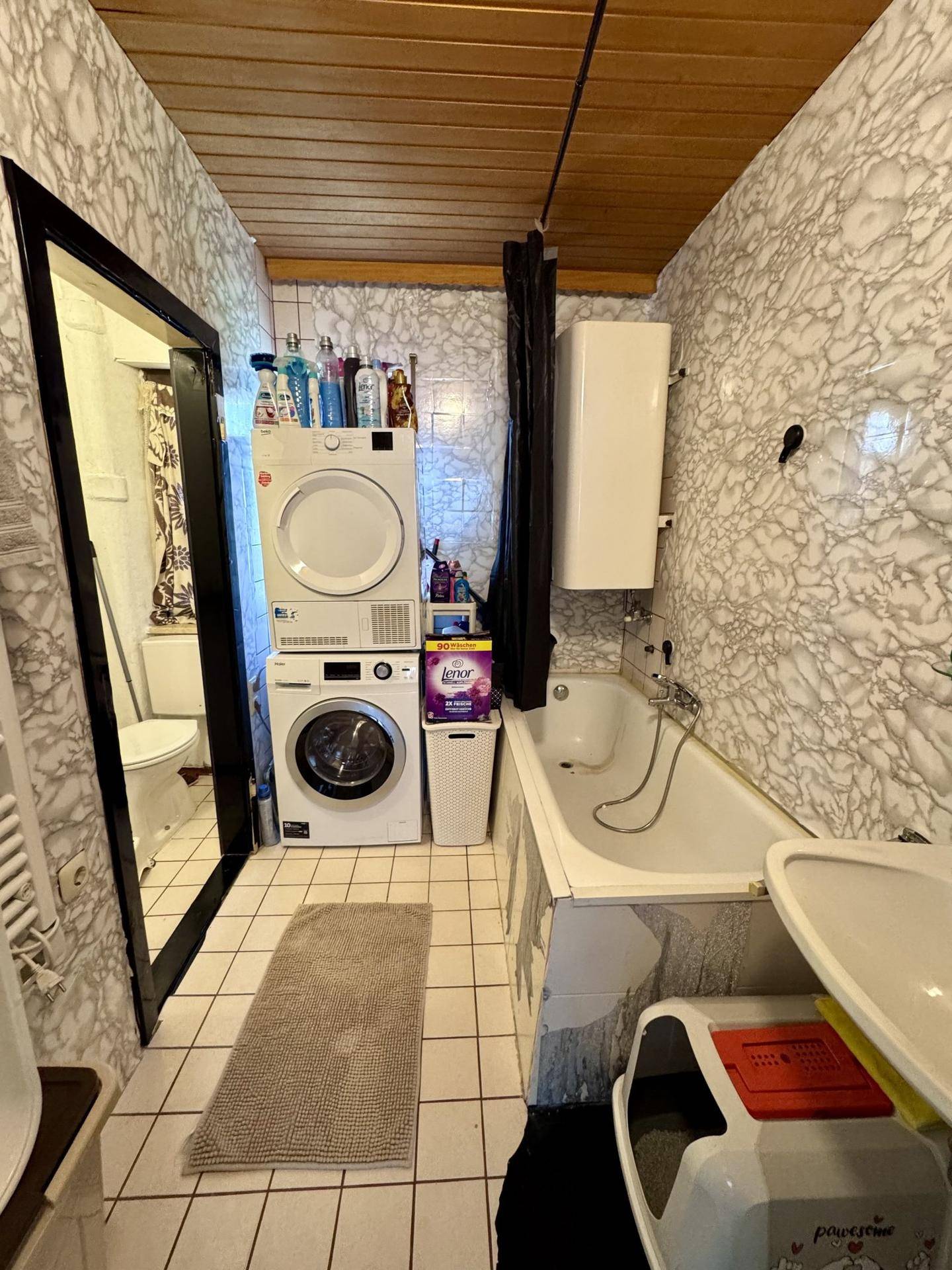 Badezimmer mit Badewanne, Waschmaschine und Trockner, sowie Holzdecke.