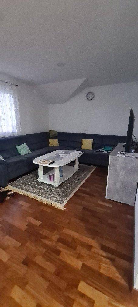 Gemütliches Wohnzimmer mit Holzboden, großem Ecksofa und Dachschräge.