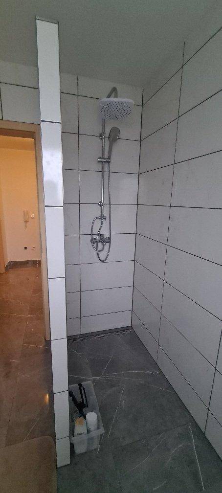 Moderne Duschkabine mit Regendusche und hellen Fliesen.
