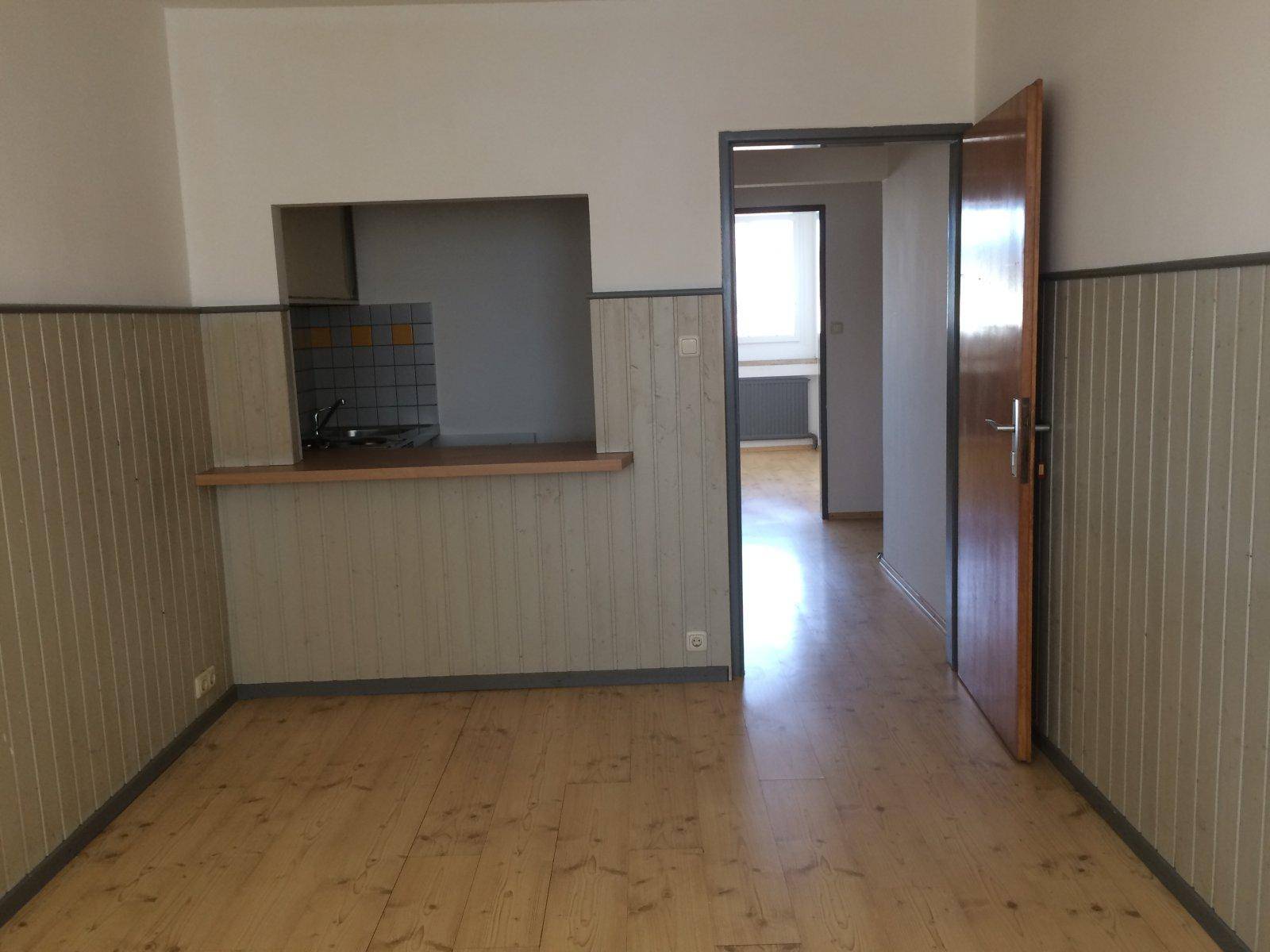 Küche mit Holzplankenboden, halbhoher Wandverkleidung und Durchreiche zum Essbereich.