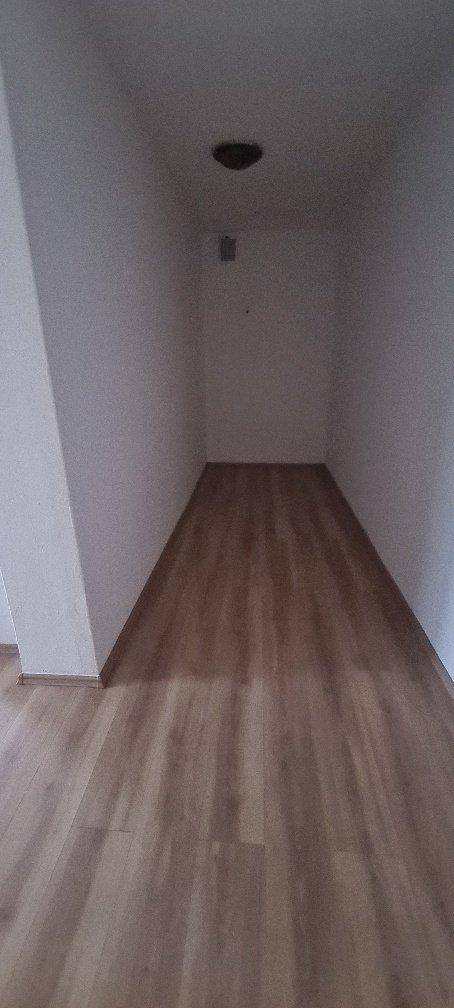 Schmaler, leerer Raum mit Laminatboden und weißen Wänden, ideal als Abstellraum.