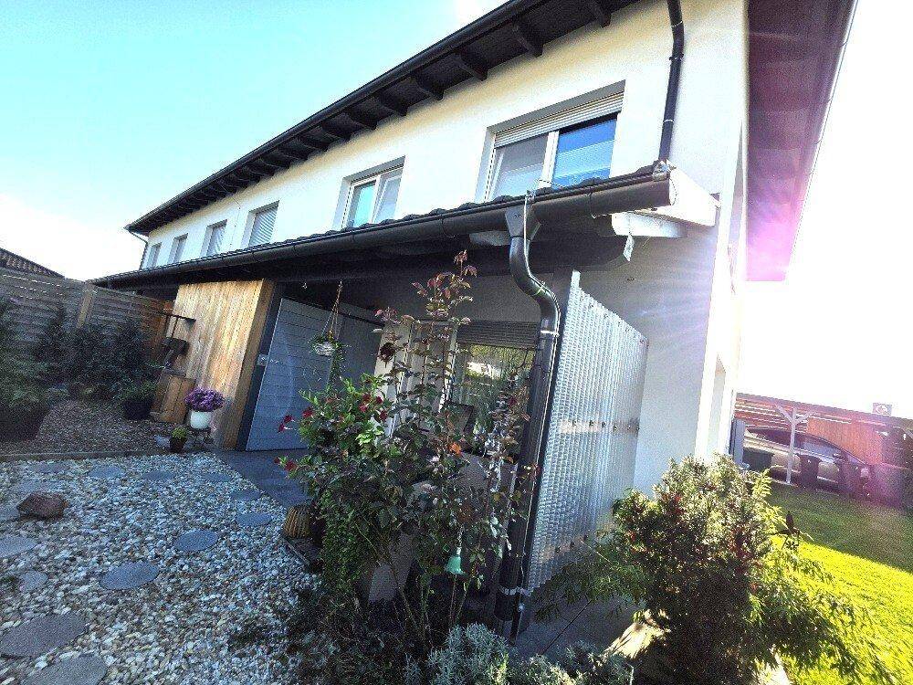 Seitlicher Eingangsbereich mit kleiner Terrasse, Kiesbeet und üppiger Bepflanzung.