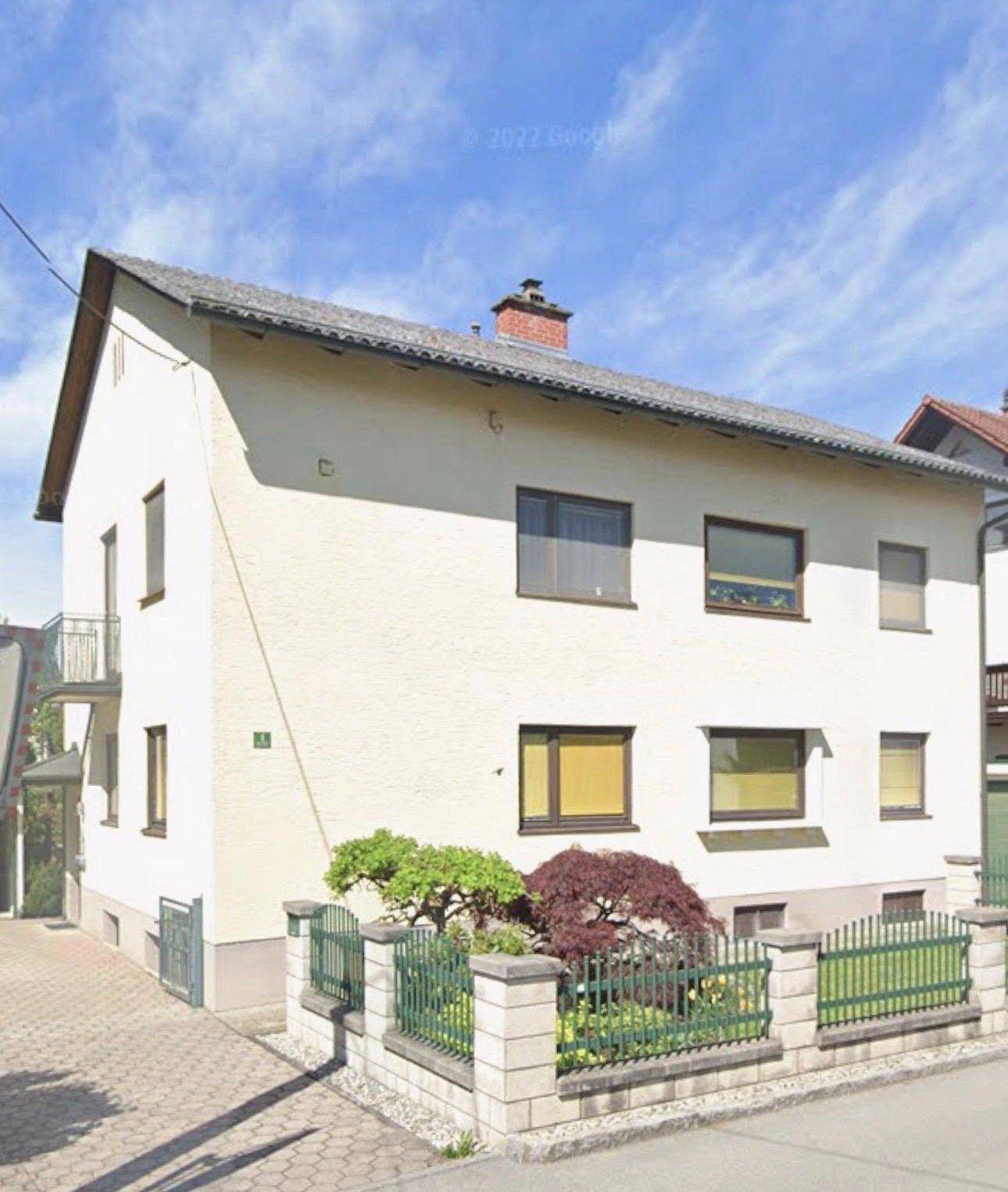 Seitenansicht des Hauses von der Straße mit gepflegtem Vorgarten und Zaun.