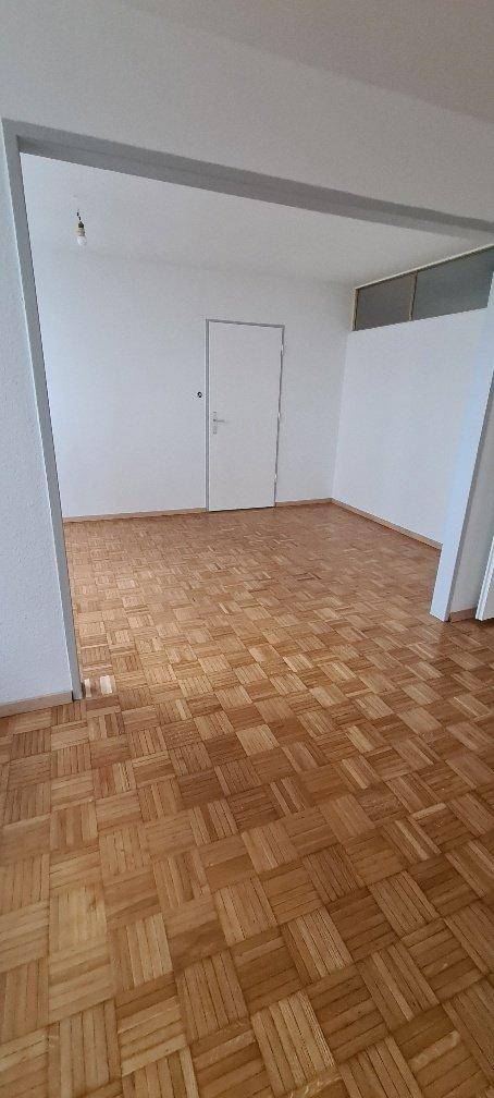 Leeres Zimmer mit klassischem Parkettboden und weißen Wänden, bereit zur individuellen Gestaltung.