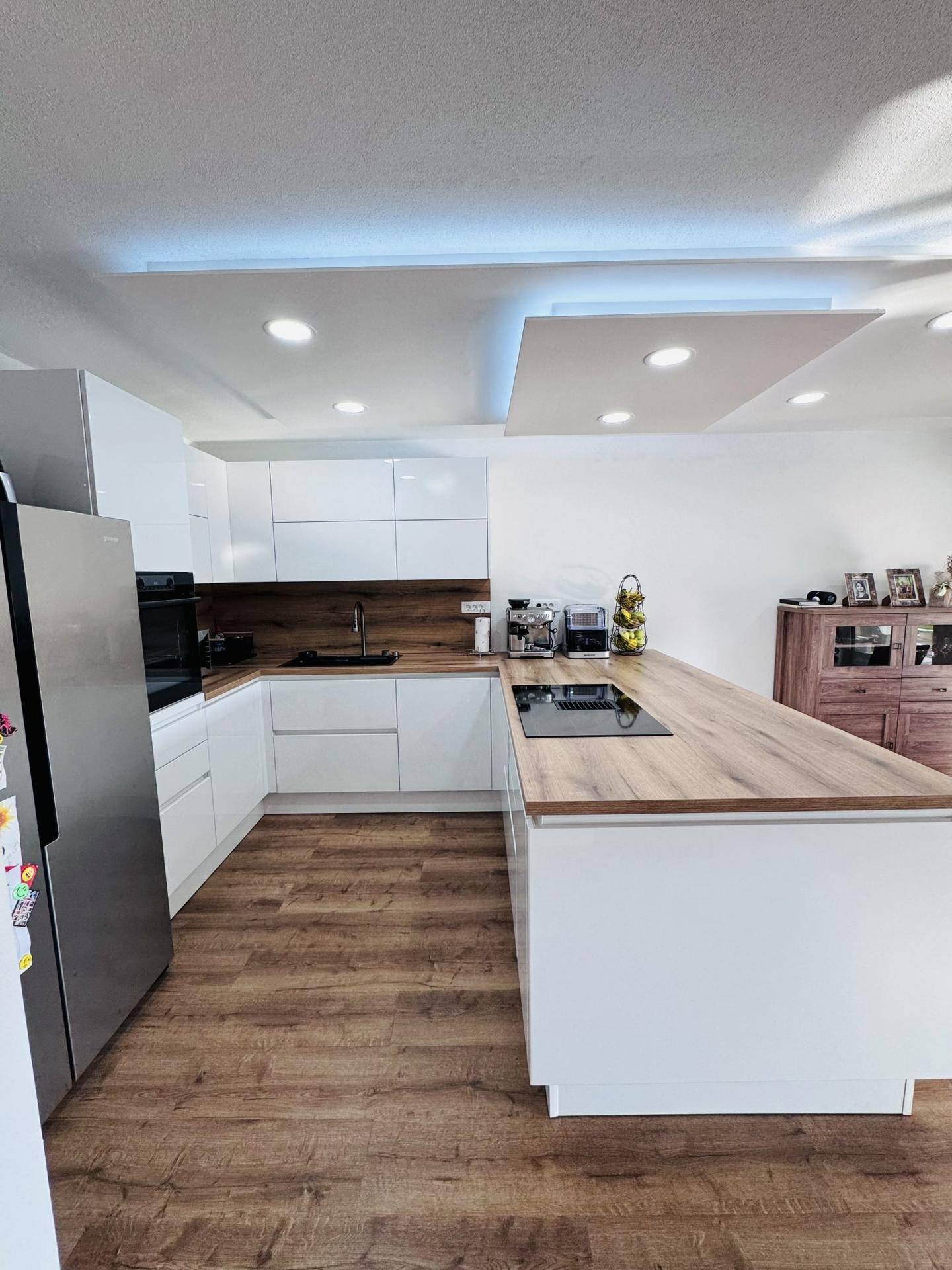 Helle, moderne Küche mit weißen Fronten, Holz-Arbeitsplatten und integrierten Geräten.