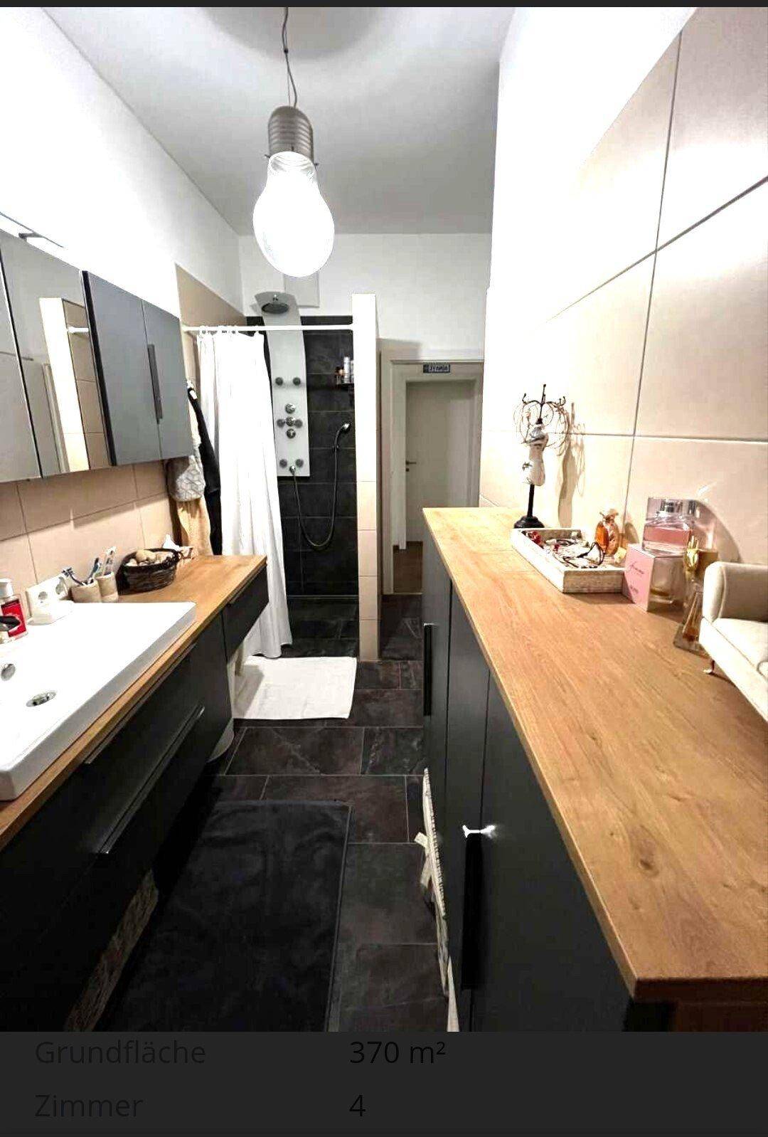 Langes Badezimmer mit Waschtisch, Duschbereich und viel Stauraum, in modernen Farben gehalten.
