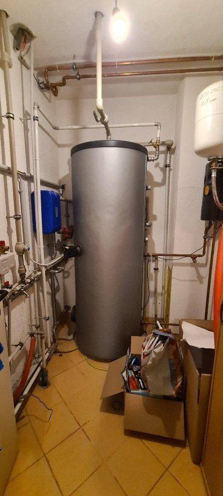 Technikraum mit Warmwasserspeicher und sichtbaren Rohrleitungen.
