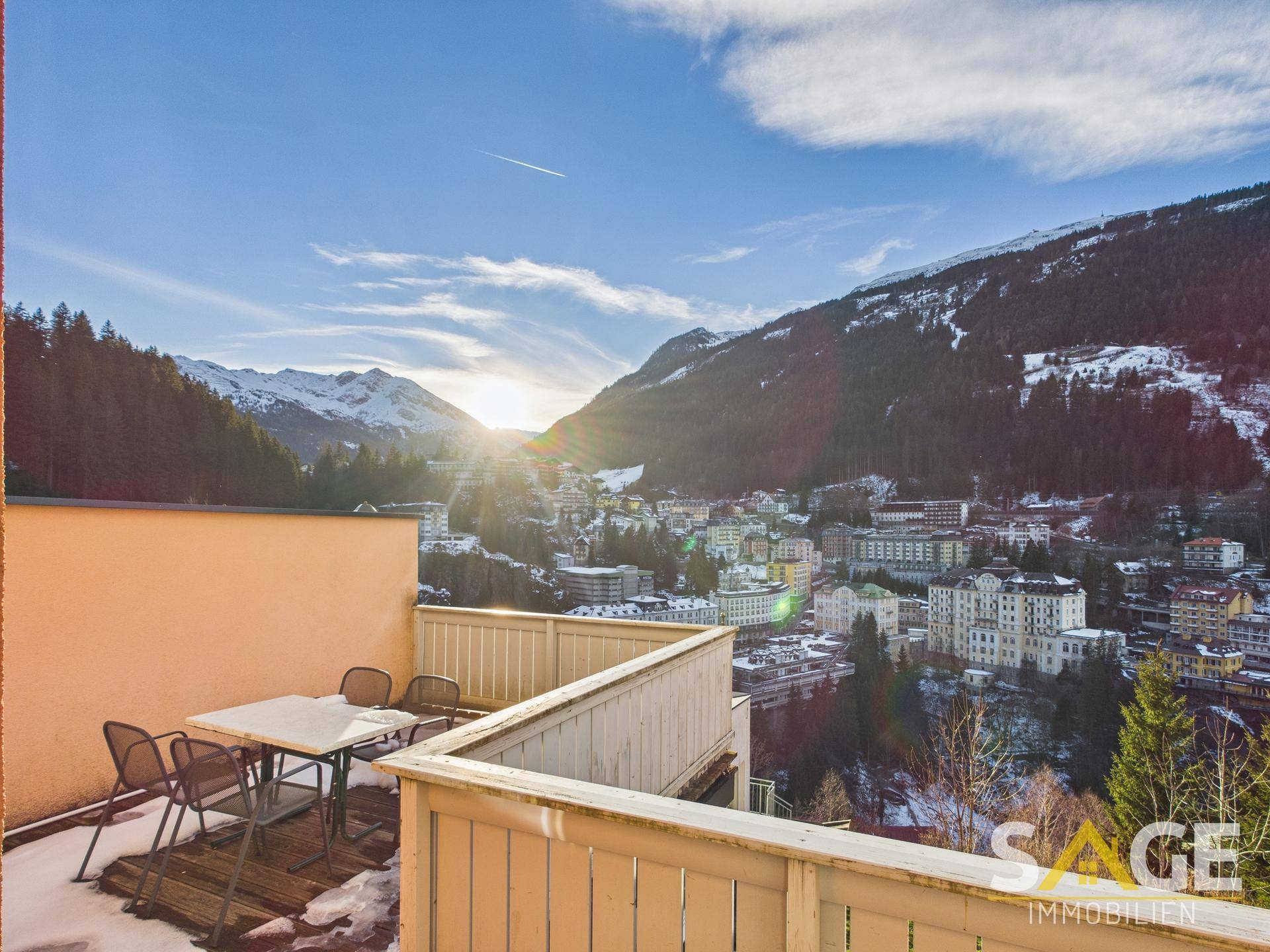 Sonniger Terrassenbereich mit Esstisch und Stühlen, bietet eine weite Aussicht auf die Berge und Stadt.