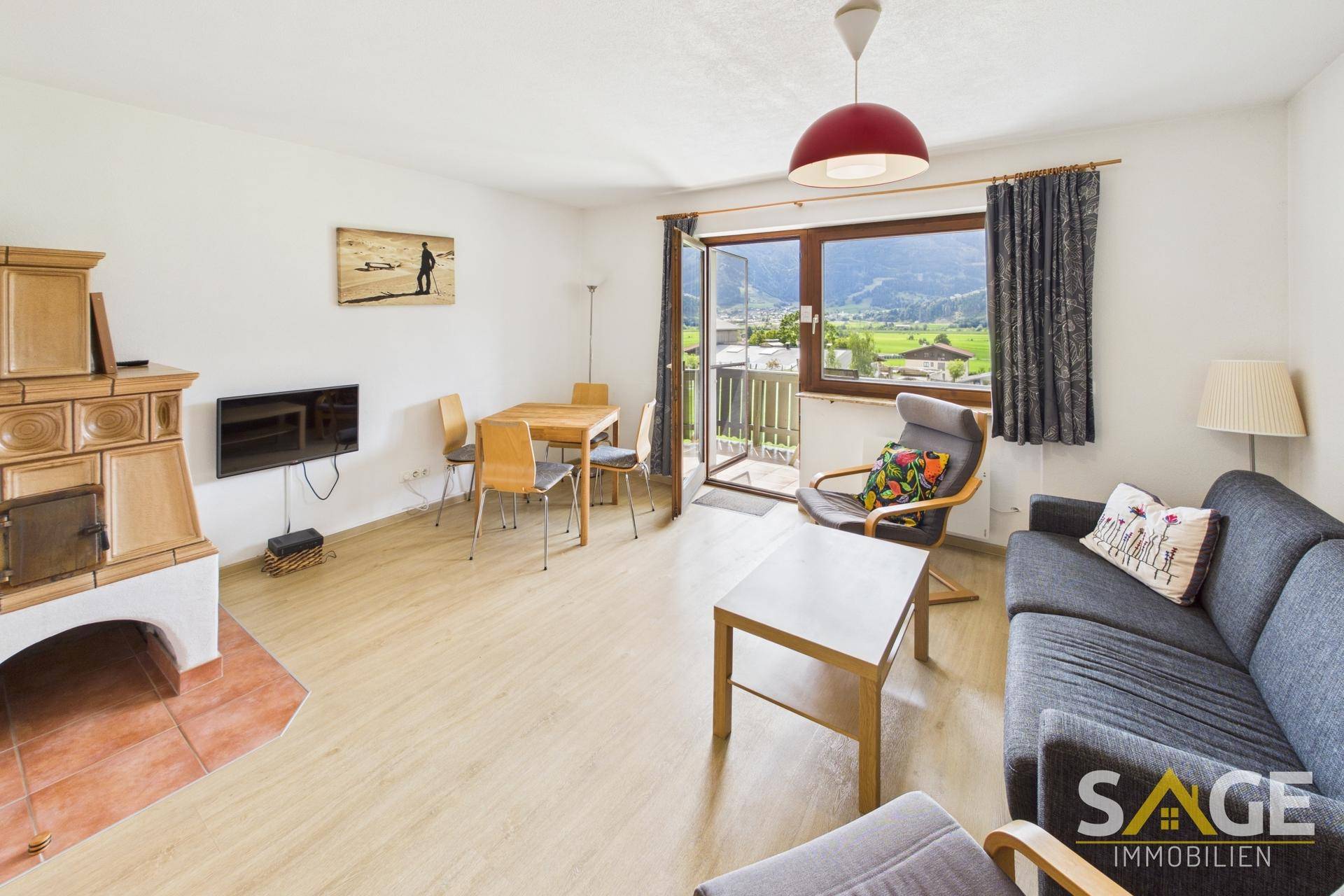 Gemütlicher Wohn-Essbereich mit Kachelofen, Balkonzugang und weitem Bergblick.