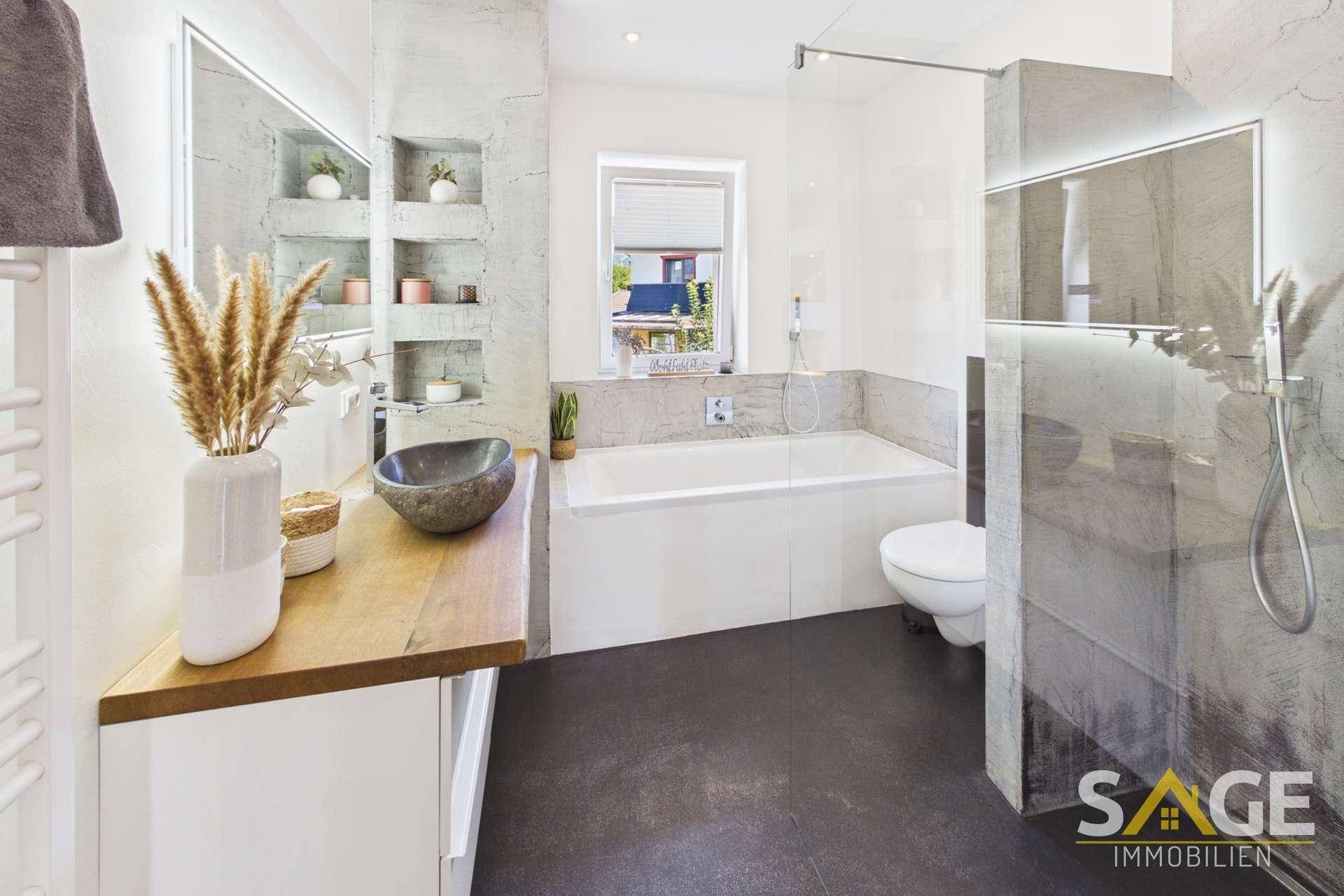 Elegantes Badezimmer mit Badewanne, bodengleicher Dusche, Holzwaschtisch und Fenster.