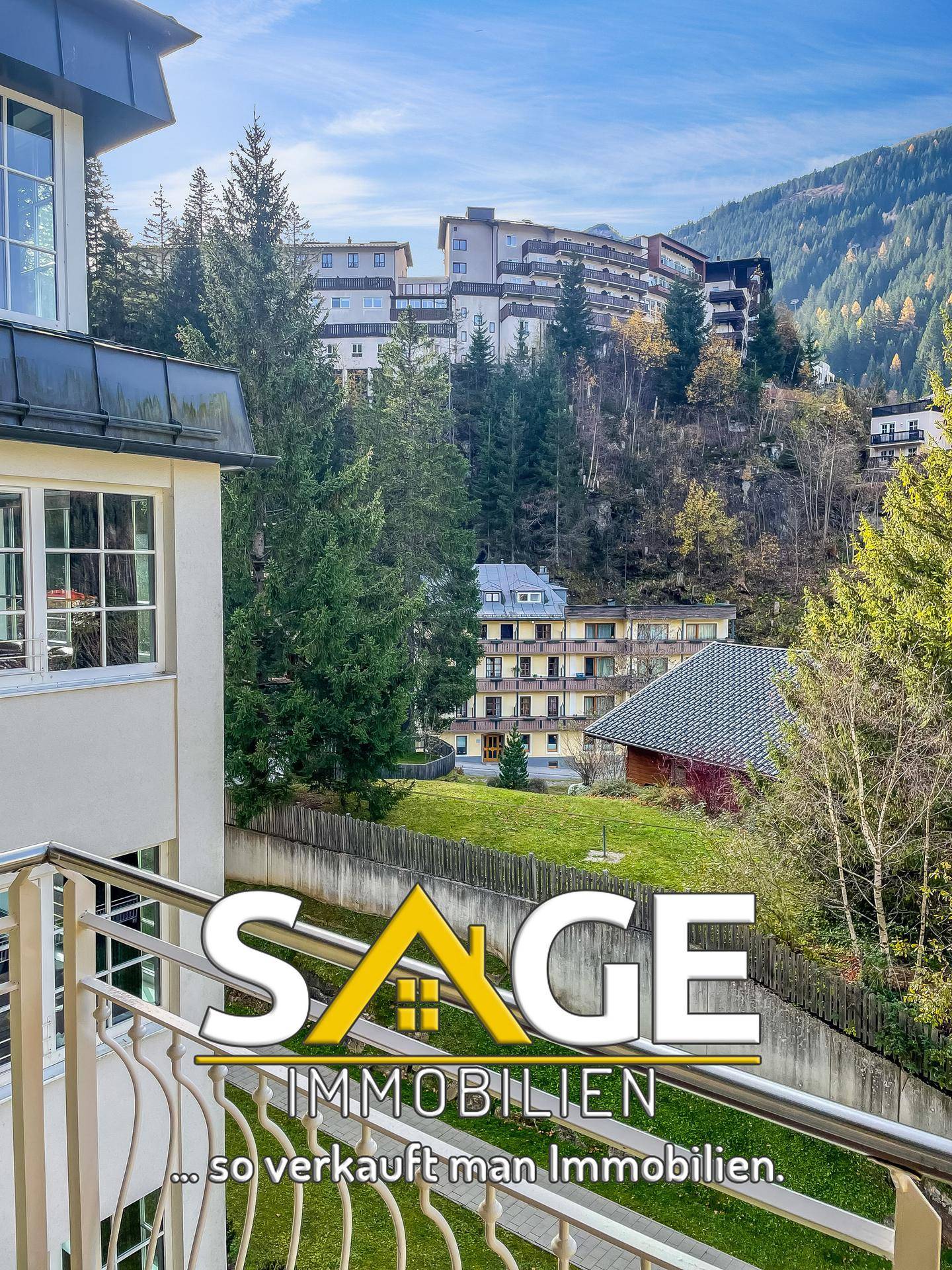 Balkon mit Blick auf die umliegende Berglandschaft und weitere Gebäude.
