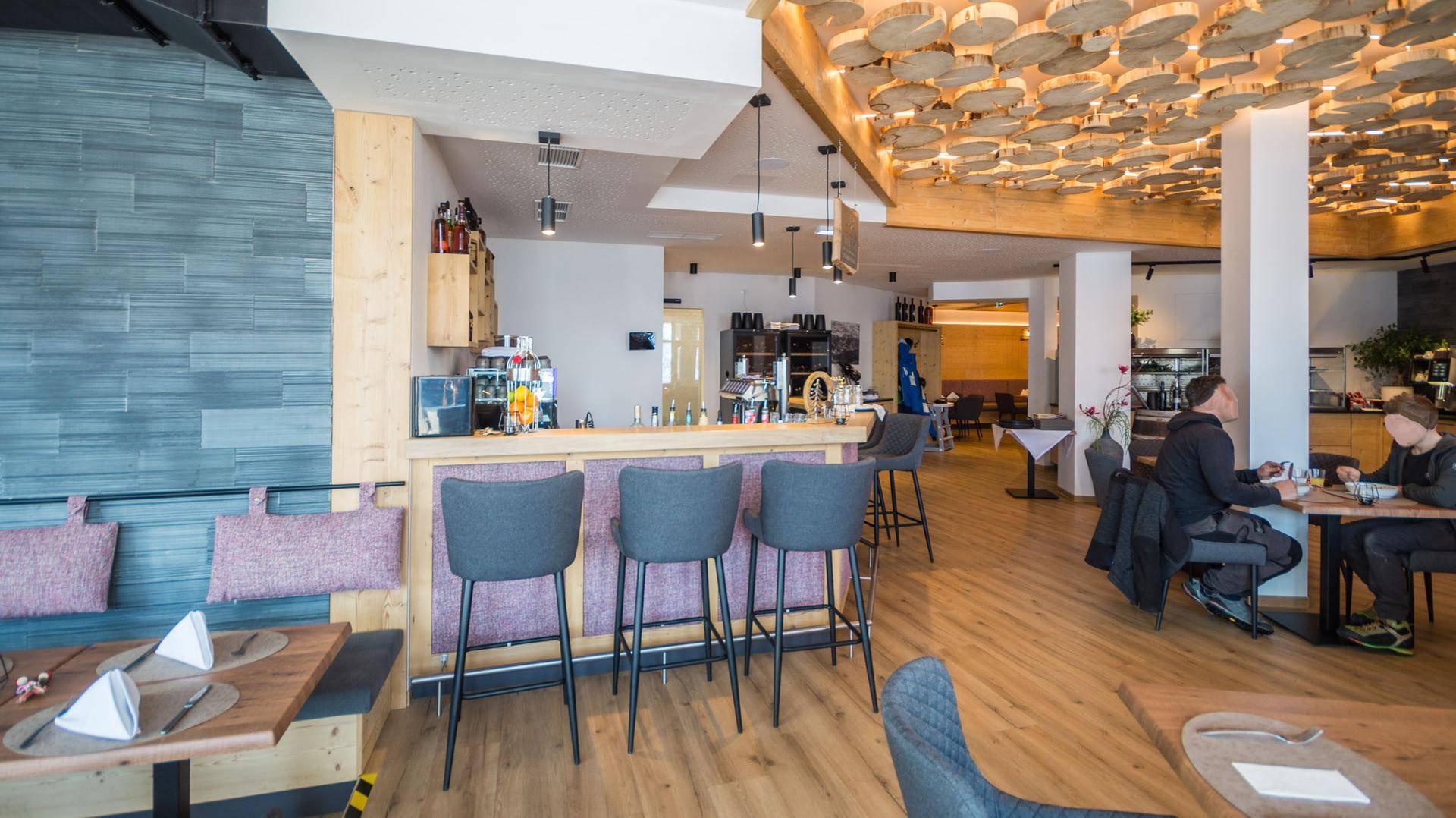 Gemütlicher Restaurant- oder Barbereich mit Holzboden, Theke und rustikaler Deckengestaltung.