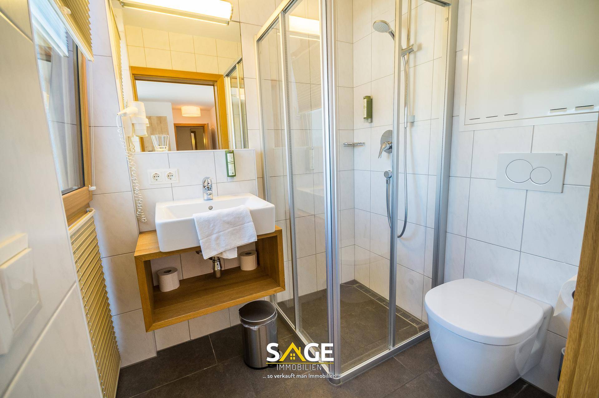 Modernes Badezimmer mit Duschkabine, Waschbecken und wandhängendem WC.