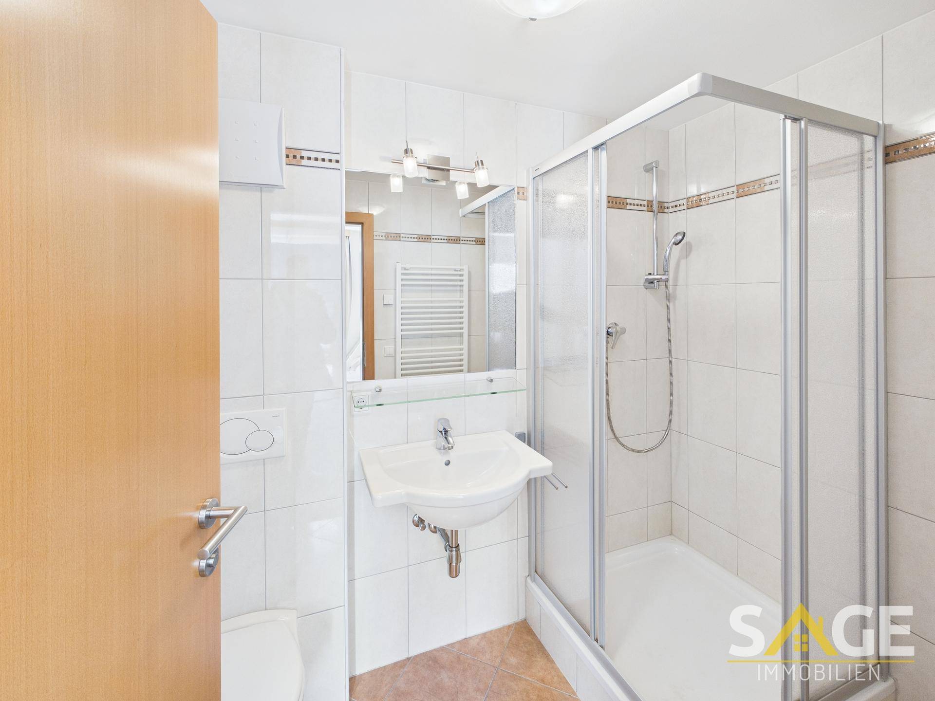 Modernes Badezimmer mit Duschkabine, Waschbecken und beheiztem Handtuchhalter.