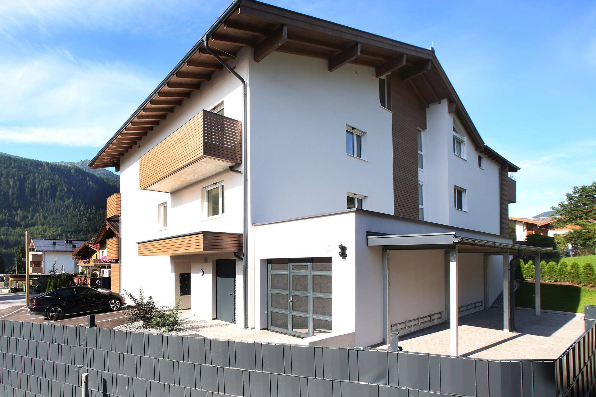 Neubau mit moderner Architektur, Carport und Garage in bergiger Umgebung.