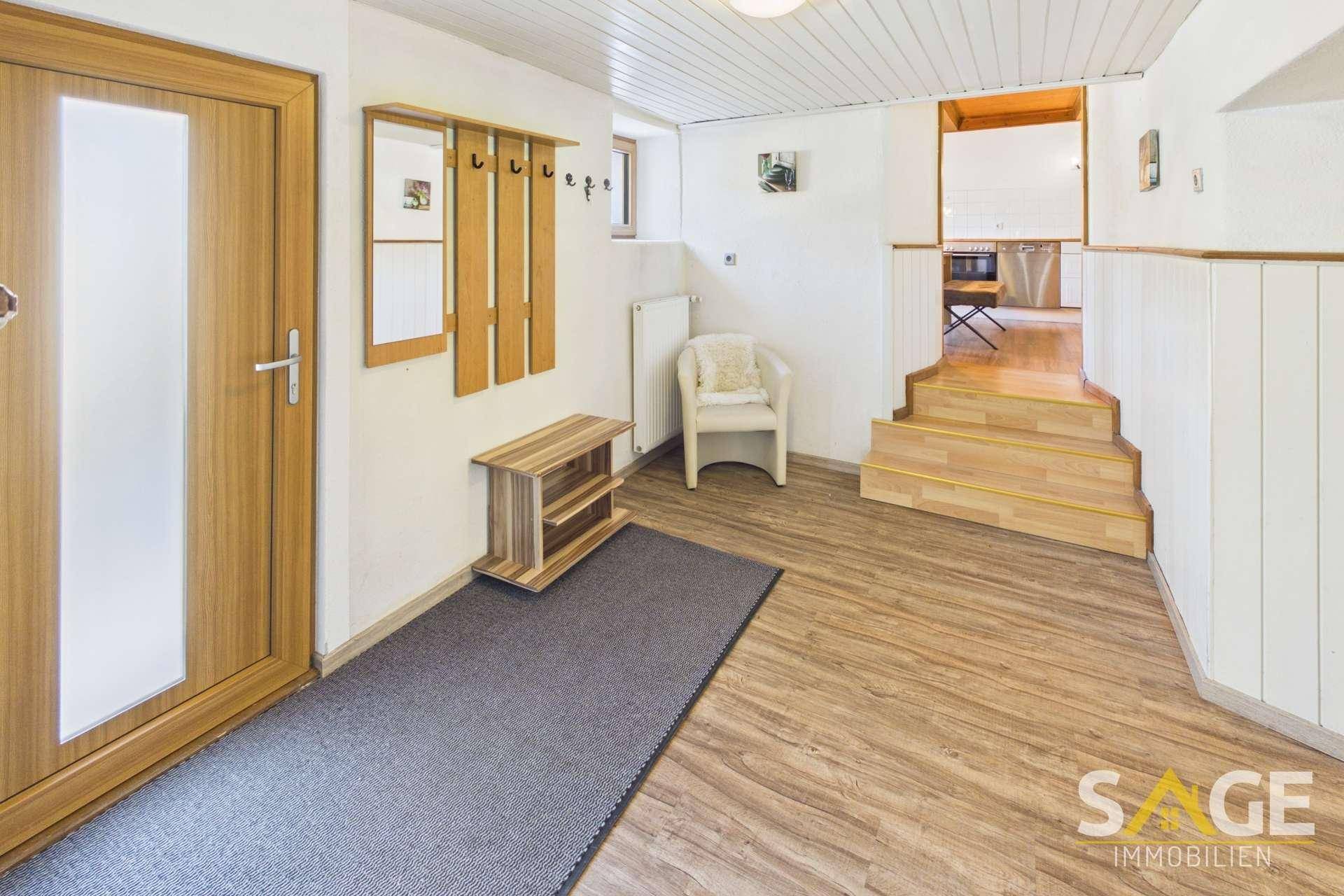 Heller Eingangsbereich mit Garderobe, Holzvertäfelung und Treppe zu den oberen Etagen.