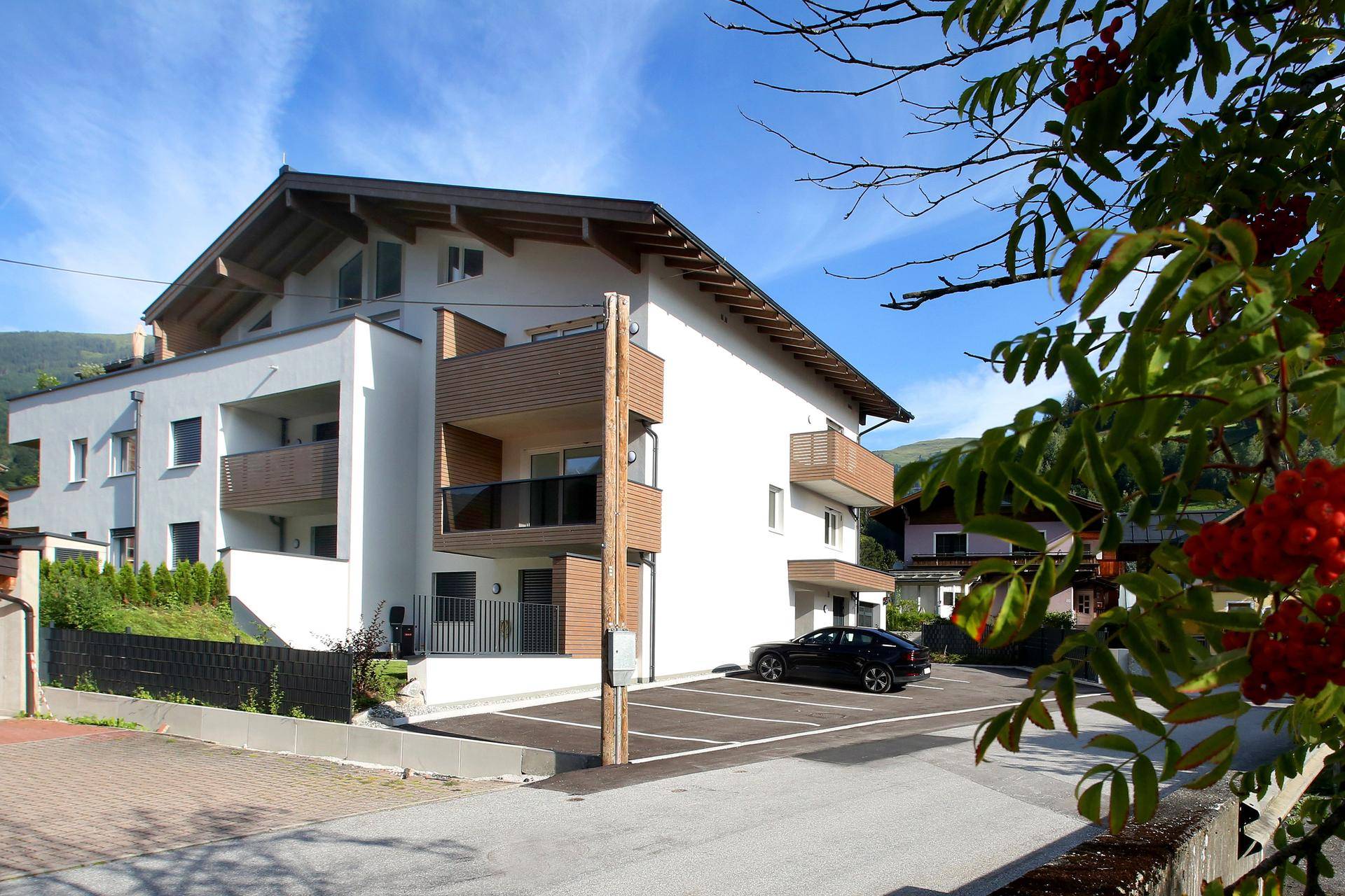 Moderne Wohnanlage mit Parkplätzen und Balkonen, umgeben von grüner Landschaft.