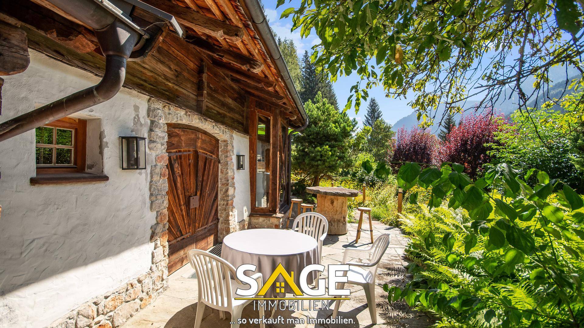 Idyllische Terrasse am Haus mit Sitzgelegenheiten, umgeben von üppiger Natur und Bergblick.