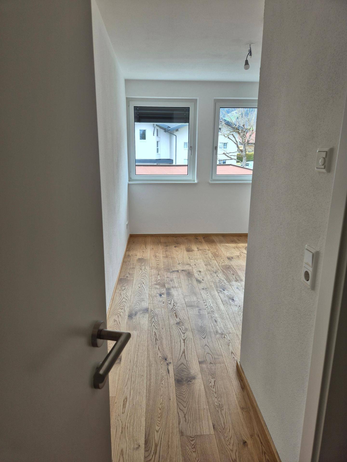 Heller Flur mit Holzboden, der den Blick in ein weiteres Zimmer freigibt.