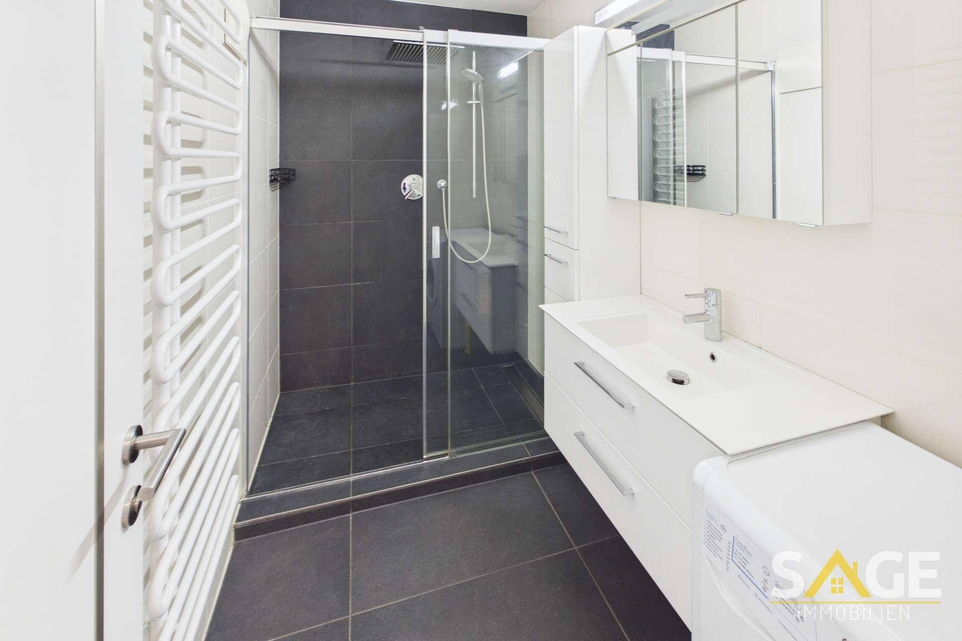 Modernes Badezimmer mit ebenerdiger Dusche, Waschbecken und beheiztem Handtuchhalter.