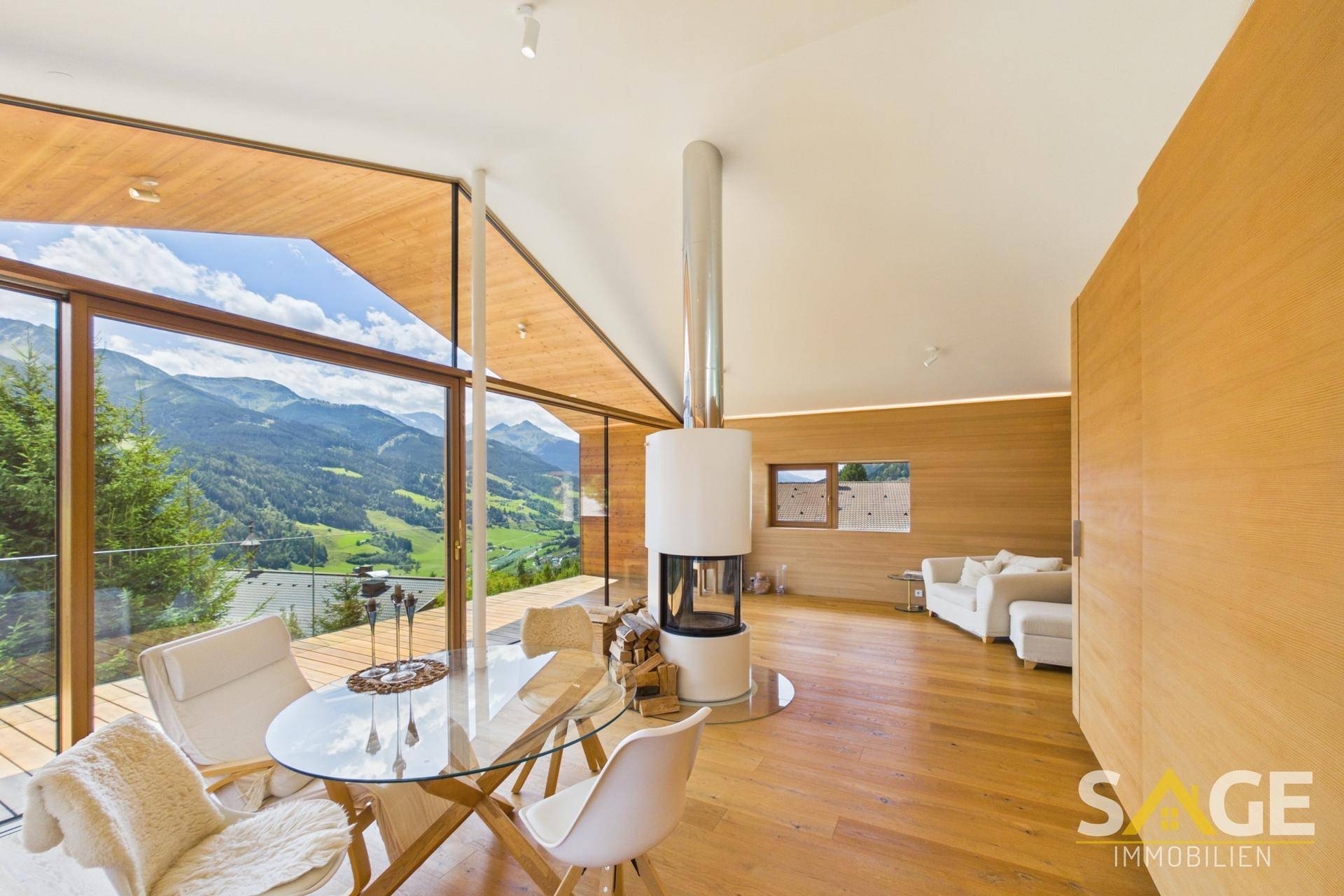 Heller Wohn- und Essbereich mit Panoramablick auf die Berge, Holzböden und einem modernen Kamin.