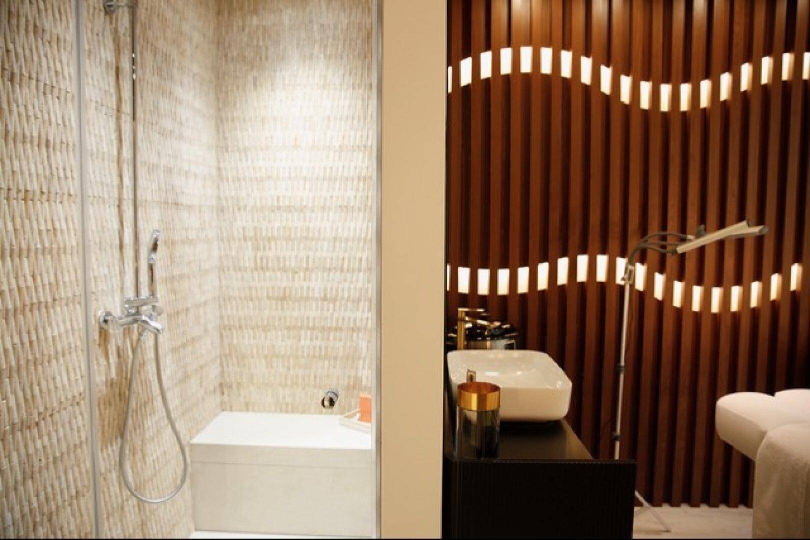 Ein modernes Badezimmer mit einer begehbaren Dusche und einer Holzlattungswand mit integrierter Beleuchtung.