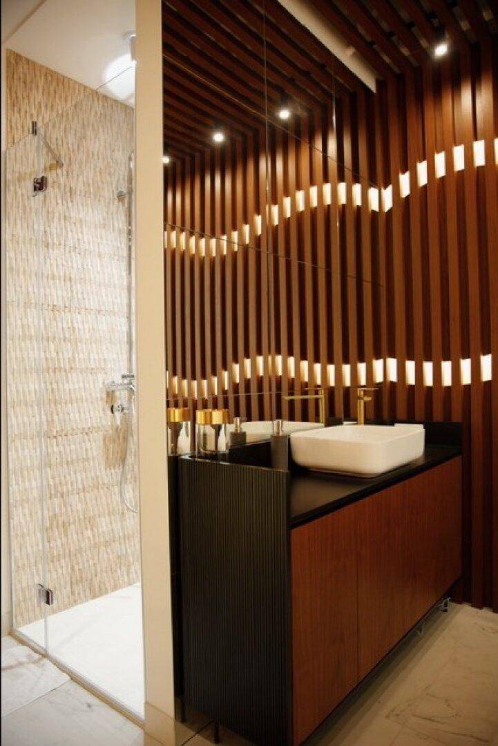 Elegantes Badezimmer mit einer begehbaren Dusche, einem Waschtisch mit Aufsatzbecken und einer Holzlattungswand.