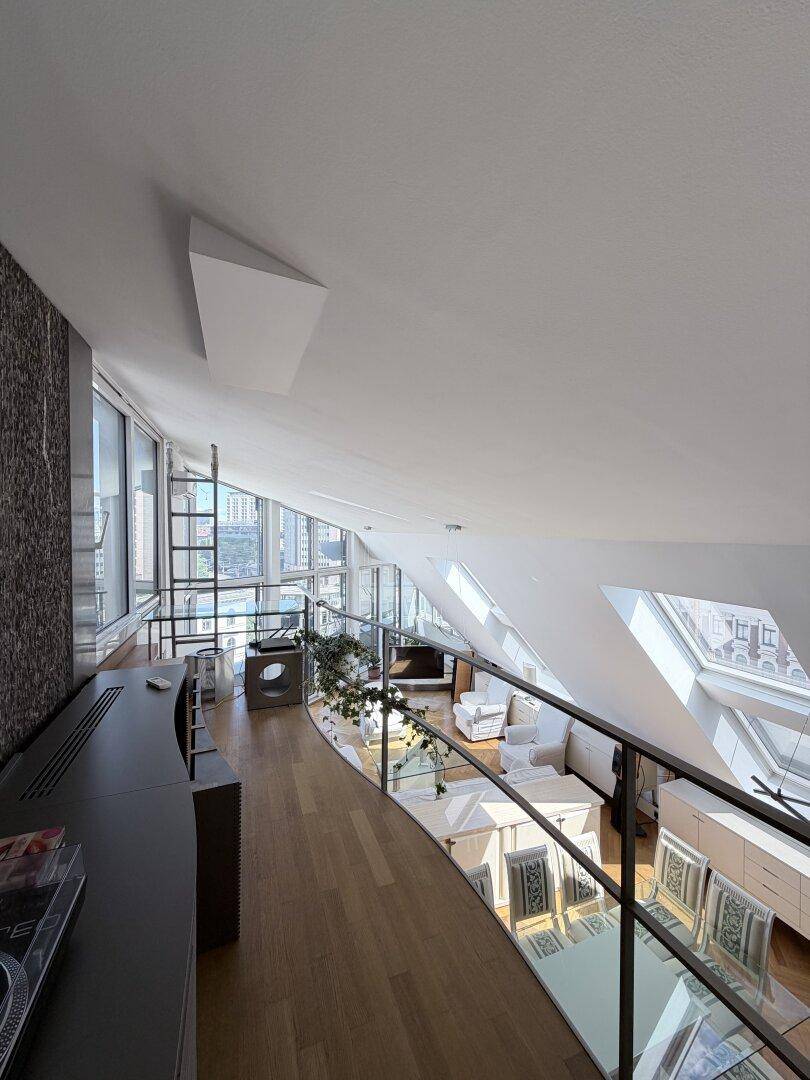 Mezzanine-Bereich mit Blick auf den offenen Wohn-Essbereich und die großen Fensterfronten.