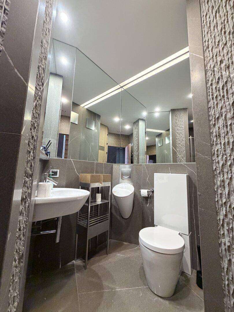 Modernes Gäste-WC mit Urinal, Wand-WC und großem Spiegel.