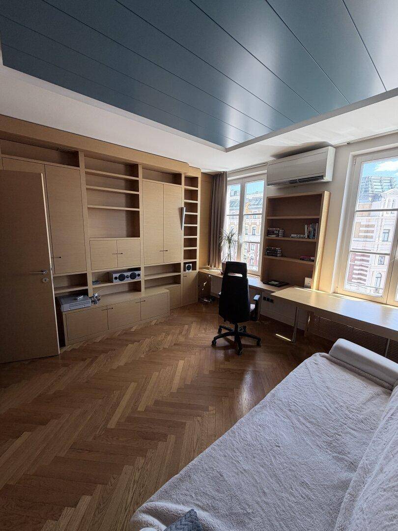 Helles Arbeitszimmer mit Einbauschränken, Parkettboden und Klimaanlage.