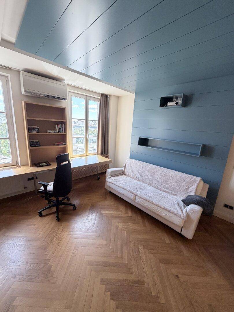 Modernes Arbeitszimmer mit Parkettboden, blauer Decke und bequemer Couch.