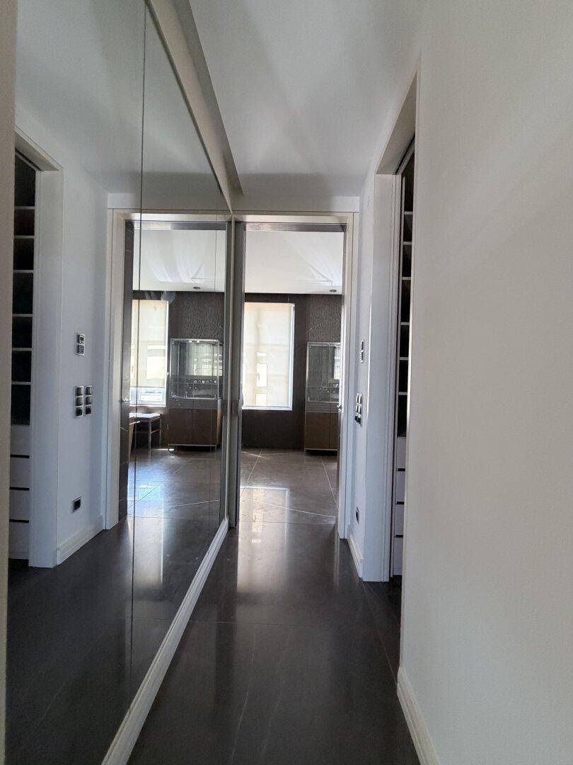 Heller Flur mit Spiegelfronten und dunklem Fliesenboden.