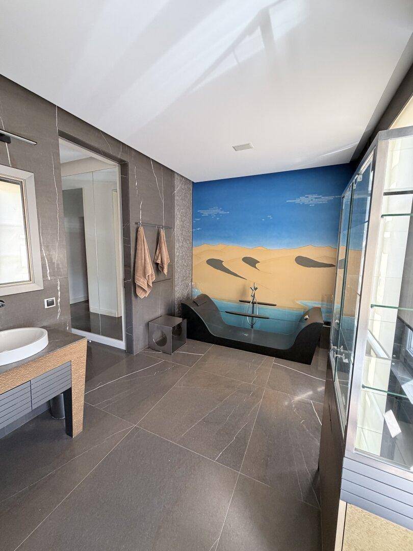 Elegantes Badezimmer mit freistehender Badewanne, Waschtisch und großem Fenster.