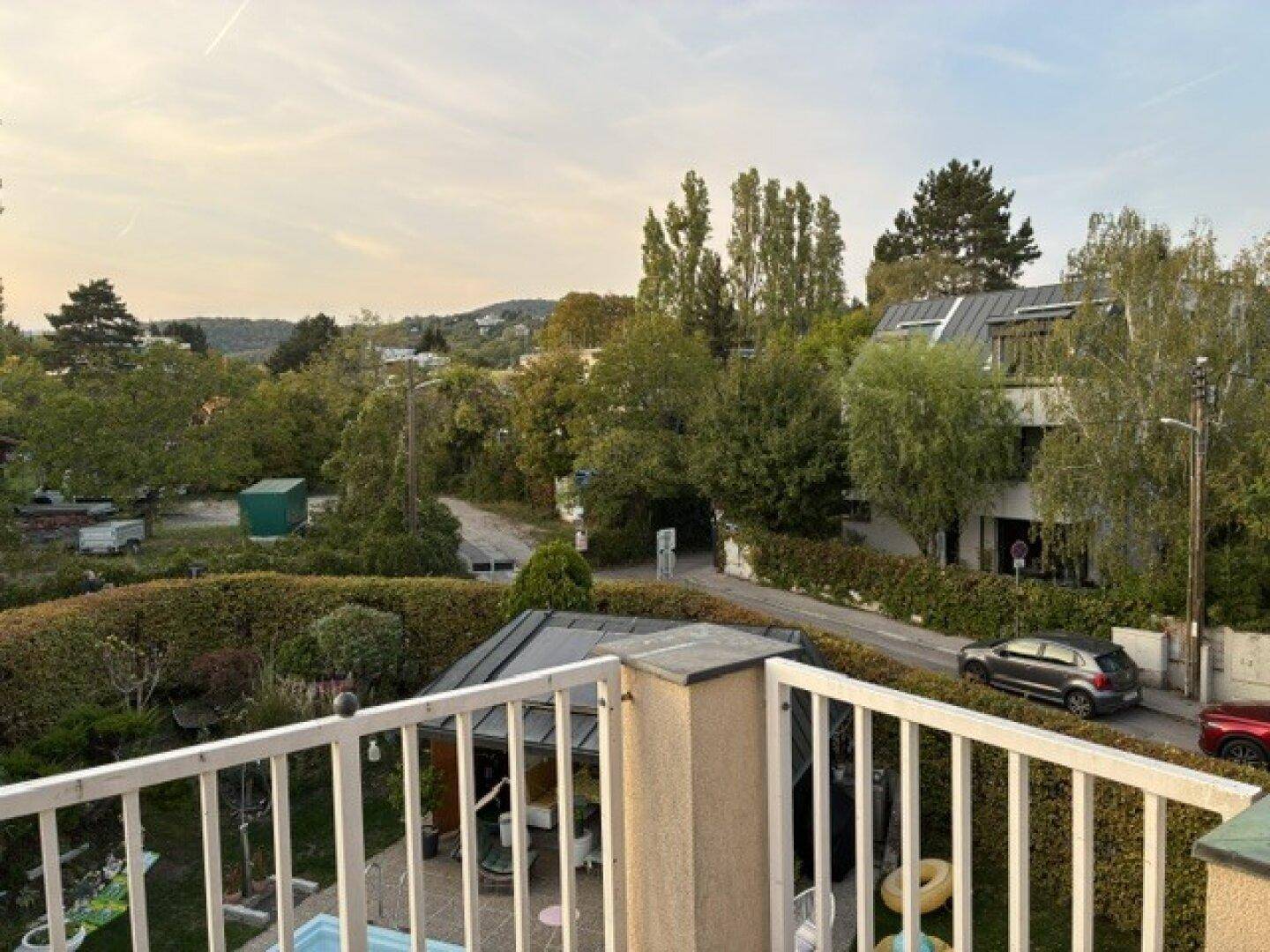 Aussicht von einem Balkon auf eine grüne Wohngegend mit Bäumen und Häusern.