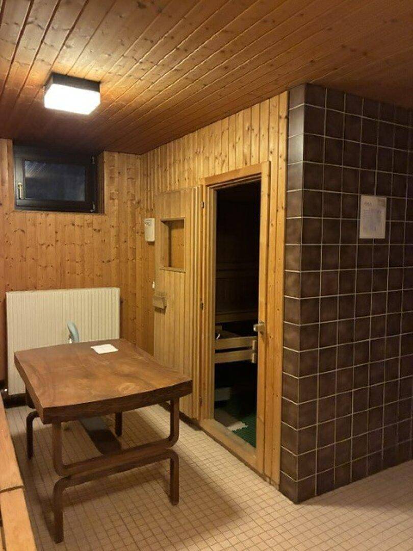 Gemütlicher Wellnessbereich mit Holzverkleidung, Fliesenboden und einer integrierten Sauna.