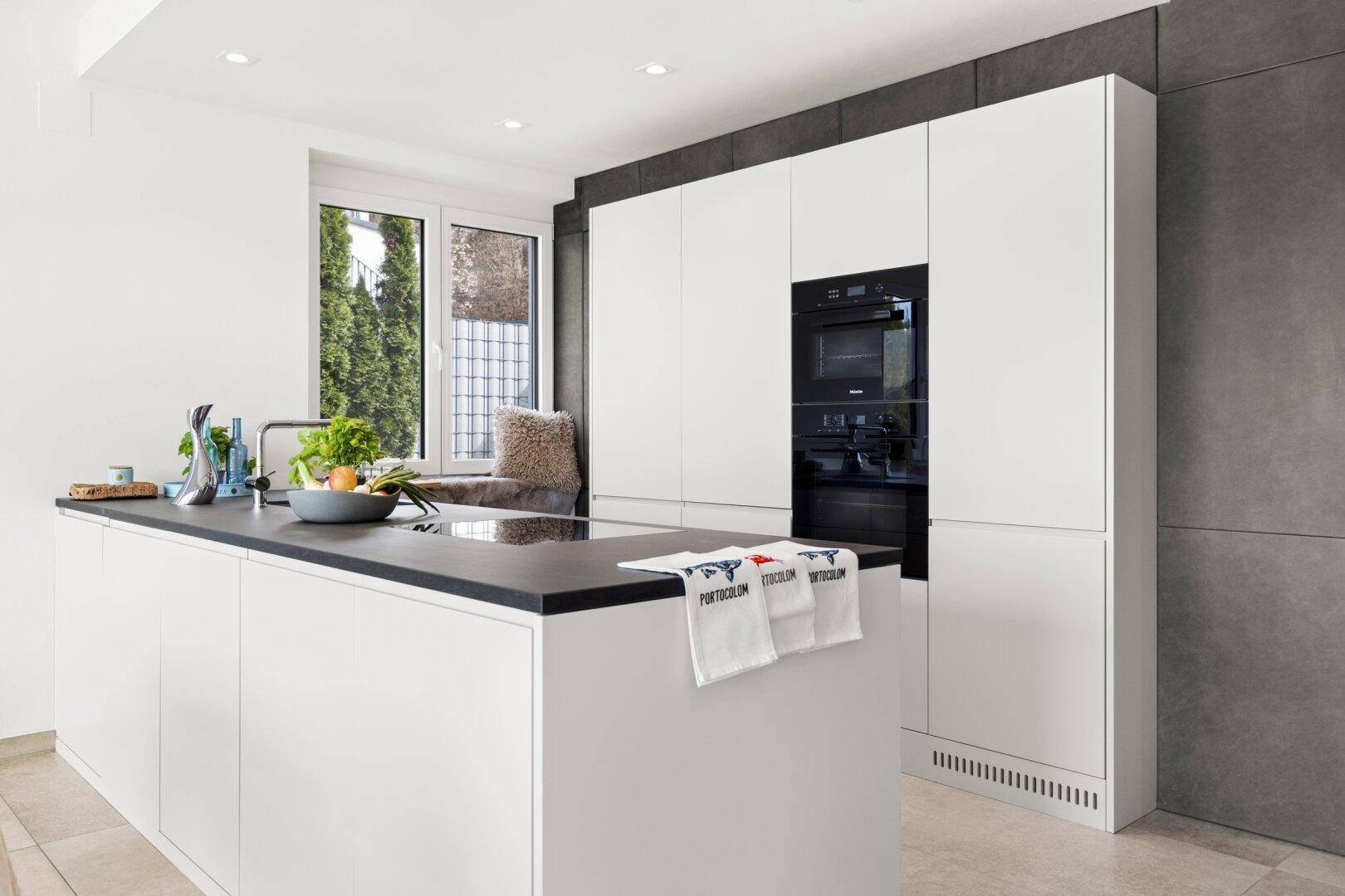 Elegante weiße Küche mit Kochinsel, integrierten Geräten und minimalistischem Design.