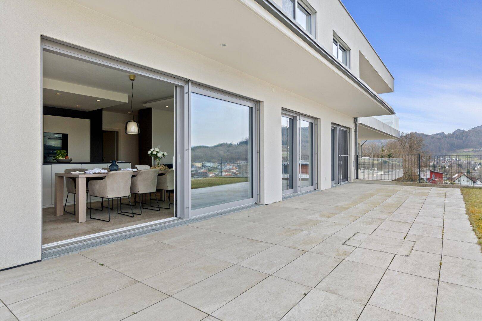 Weitläufige Terrasse mit großen Schiebetüren, die zum offenen Wohnbereich führen.
