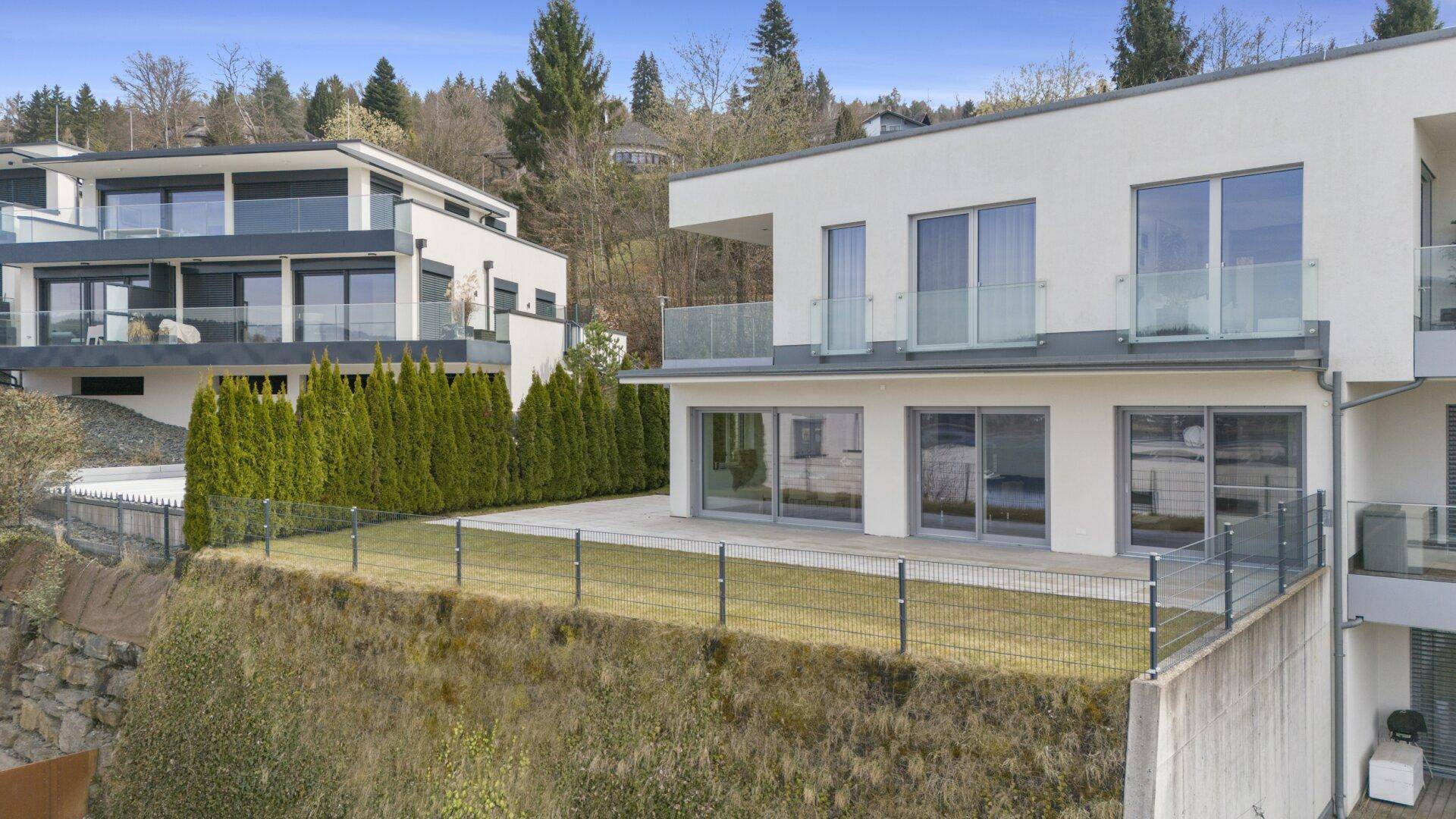 Moderne Wohnanlage mit mehreren Einheiten, Terrassen und gepflegter Außenanlage am Hang.
